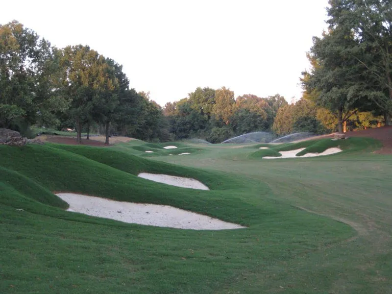 A green at Mirimichi guarded by two broad sand bunkers, with autumn trees behind.